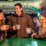 Drei Personen geniessen einen Glühwein am Basler Weihnachtsmarkt.