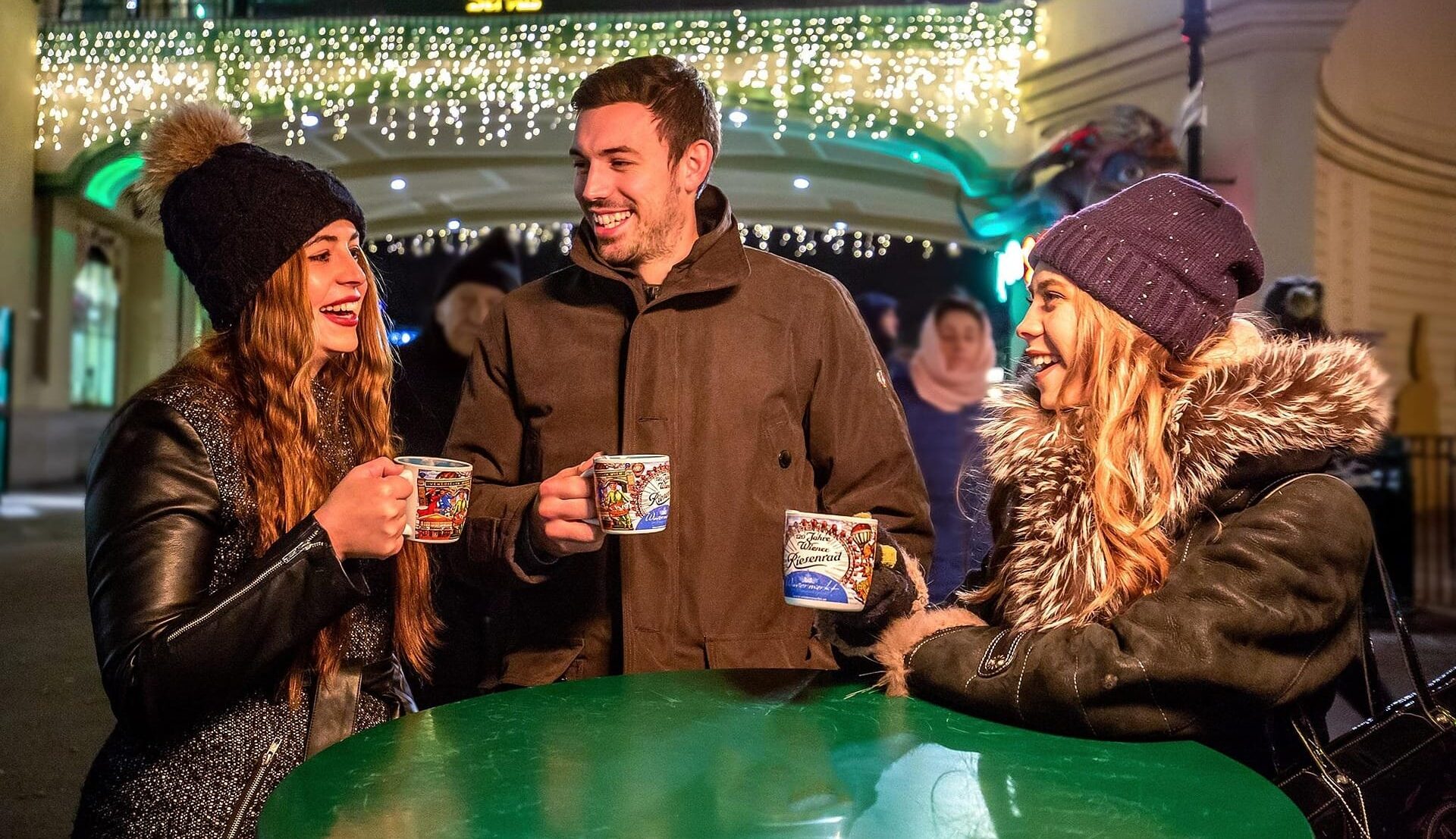 Drei Personen geniessen einen Glühwein am Basler Weihnachtsmarkt.